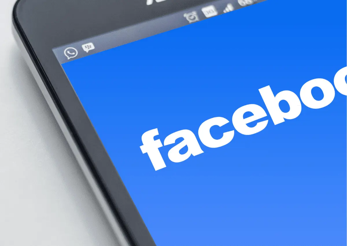 Smartphone screen displaying the Facebook logo on a blue background, viewed at an angle.