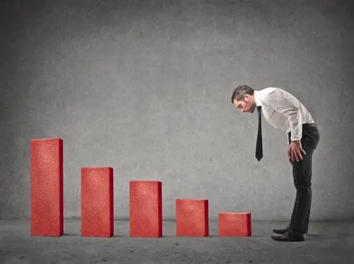 Concerned businessman looking at declining red bar chart