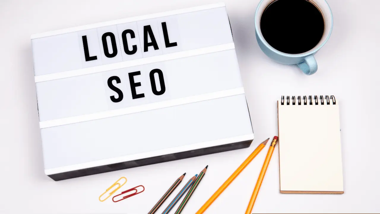 Cup Of Coffee, A Notepad And Stationary. With A Small Signboard Reading, "Local SEO"