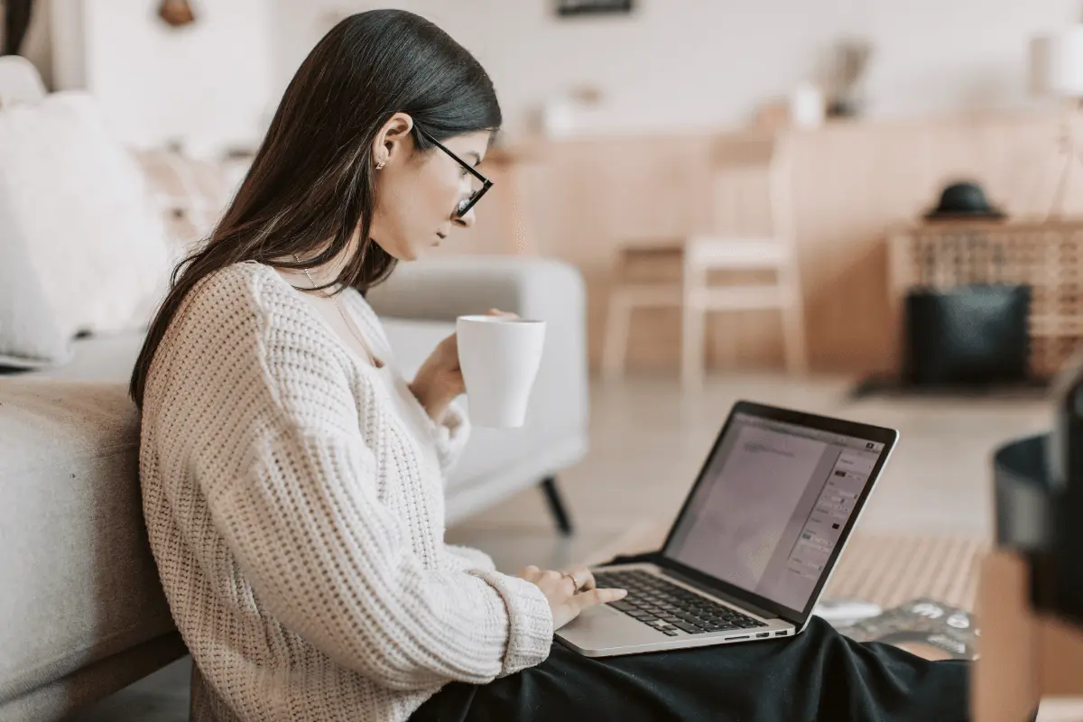 A woman sitting in front of her laptop holding a cup of coffee